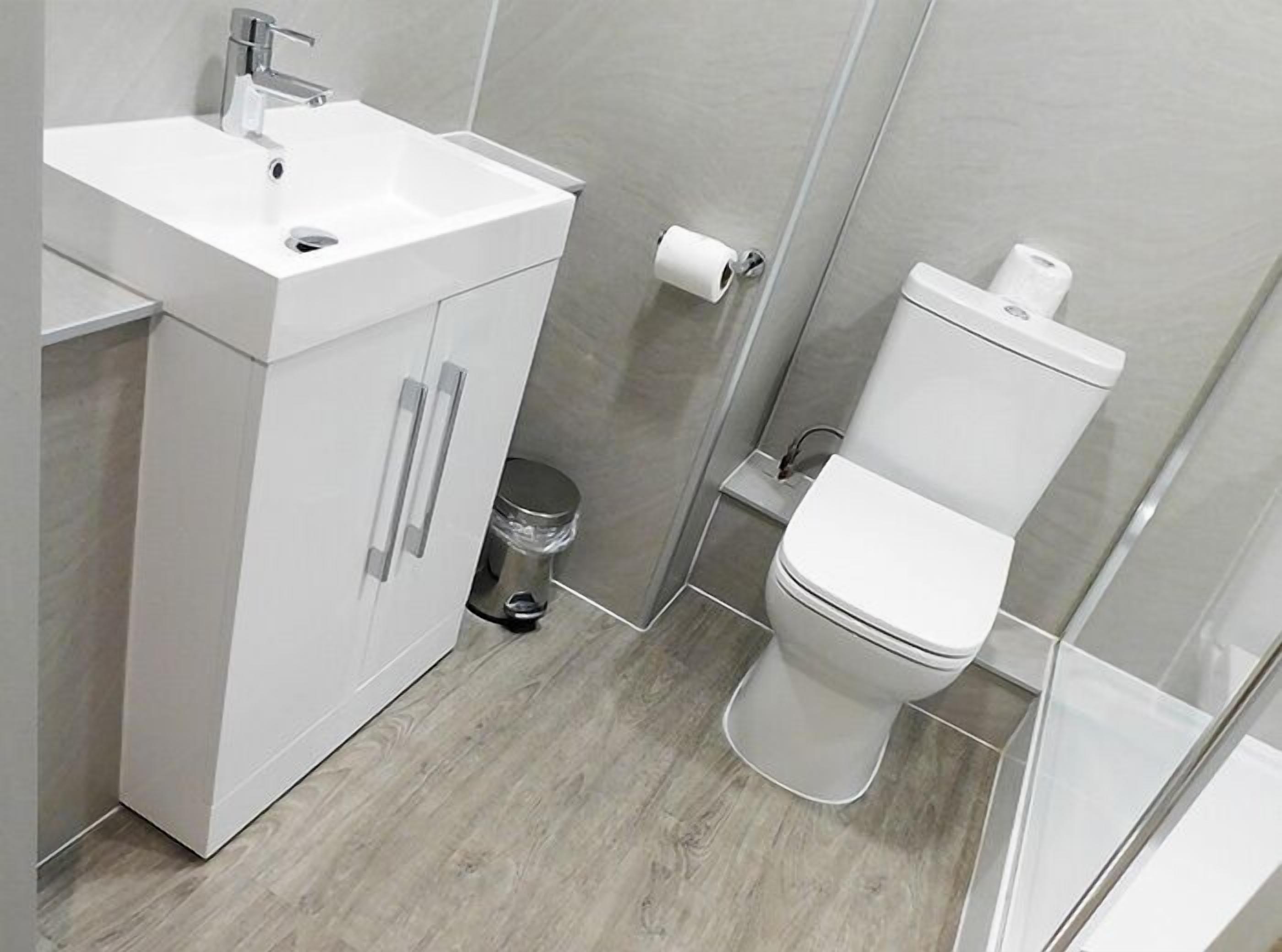 A modern bathroom with a white sink, cabinet, and toilet.