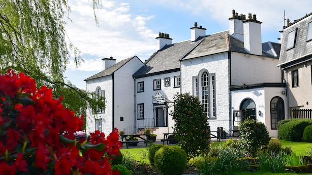 A traditional white building with a central arched window and a sign above the entrance.