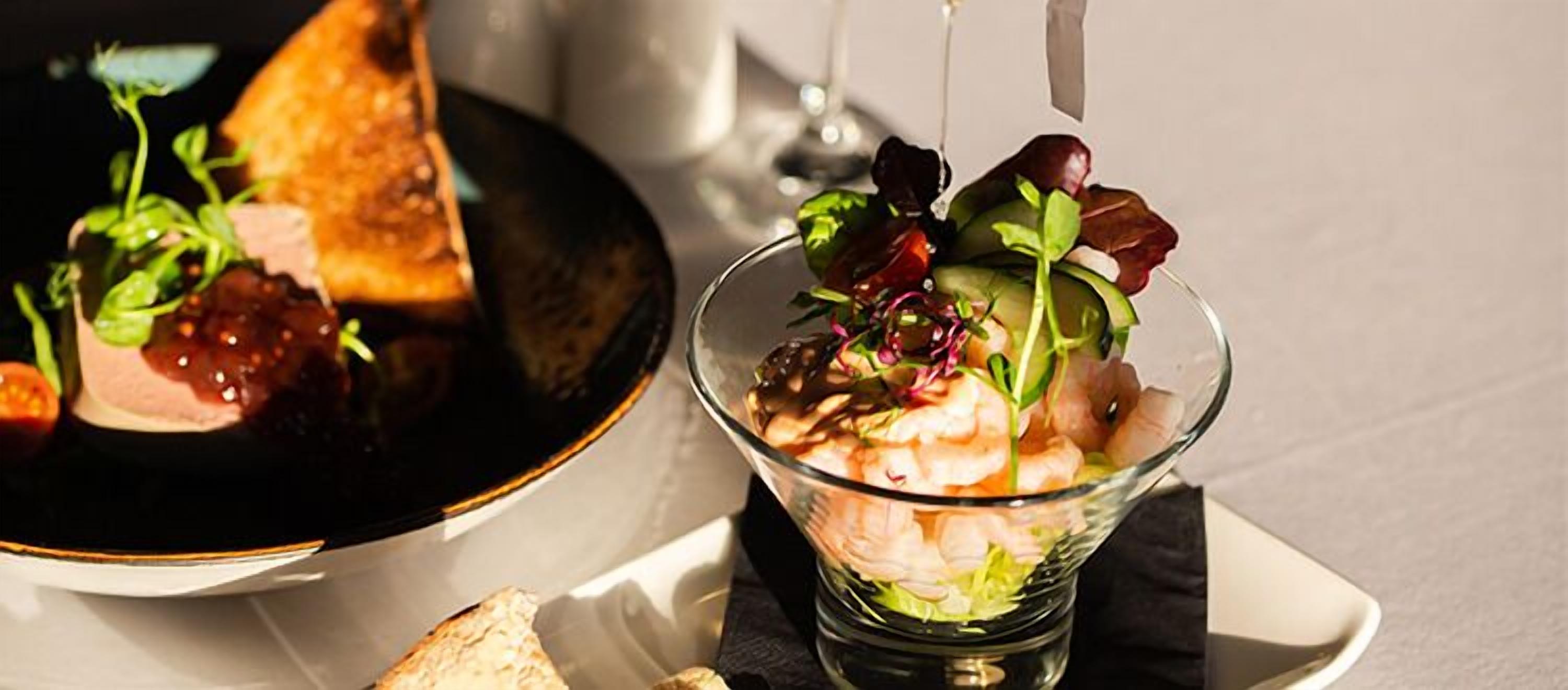 A dining table with a plate of food and a glass bowl of salad.