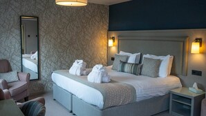 A hotel room with a large bed, two bedside tables, a chair, a desk, and a mirror.