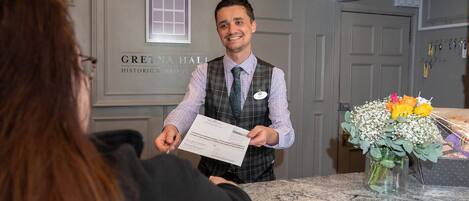 A hotel reception area with a marble counter, a nameplate, and a bouquet of flowers.