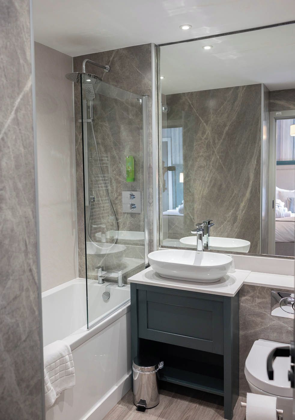 A modern bathroom with a glass-enclosed shower, a white sink, and a dark vanity.
