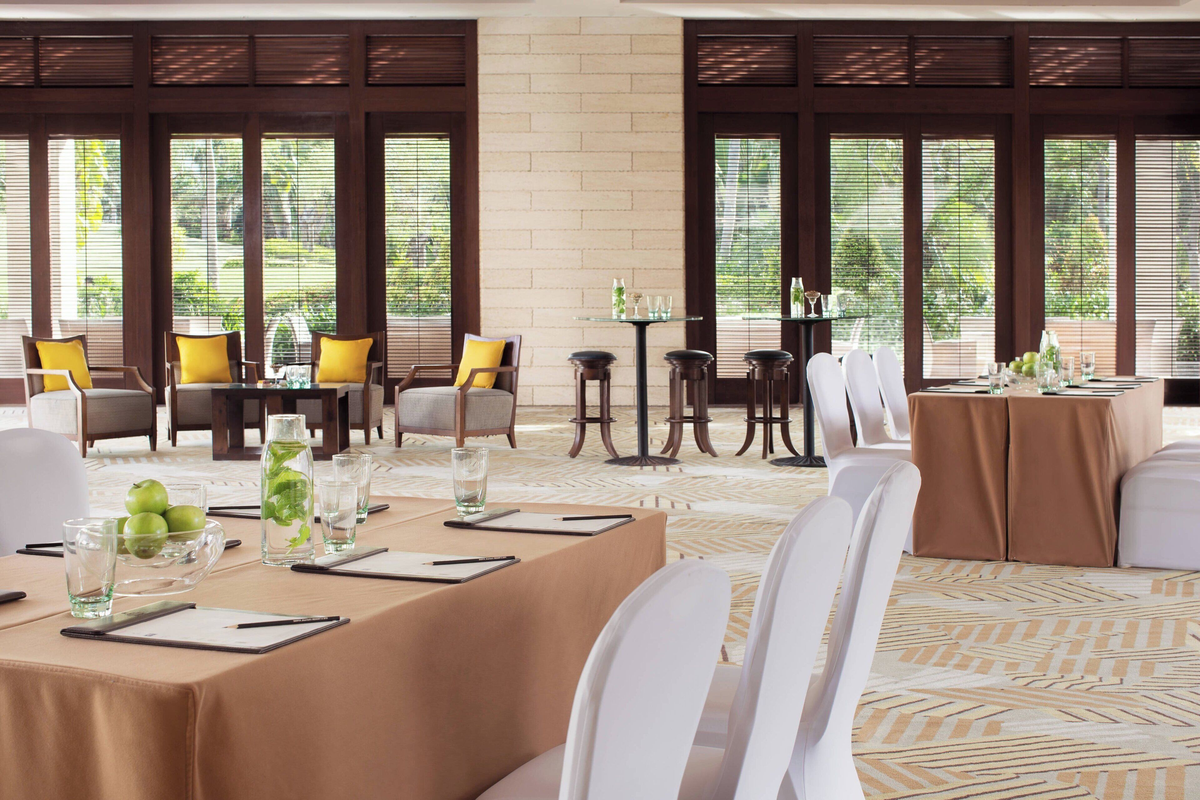 A dining area with tables set for a meal, chairs, and a bar area with stools.