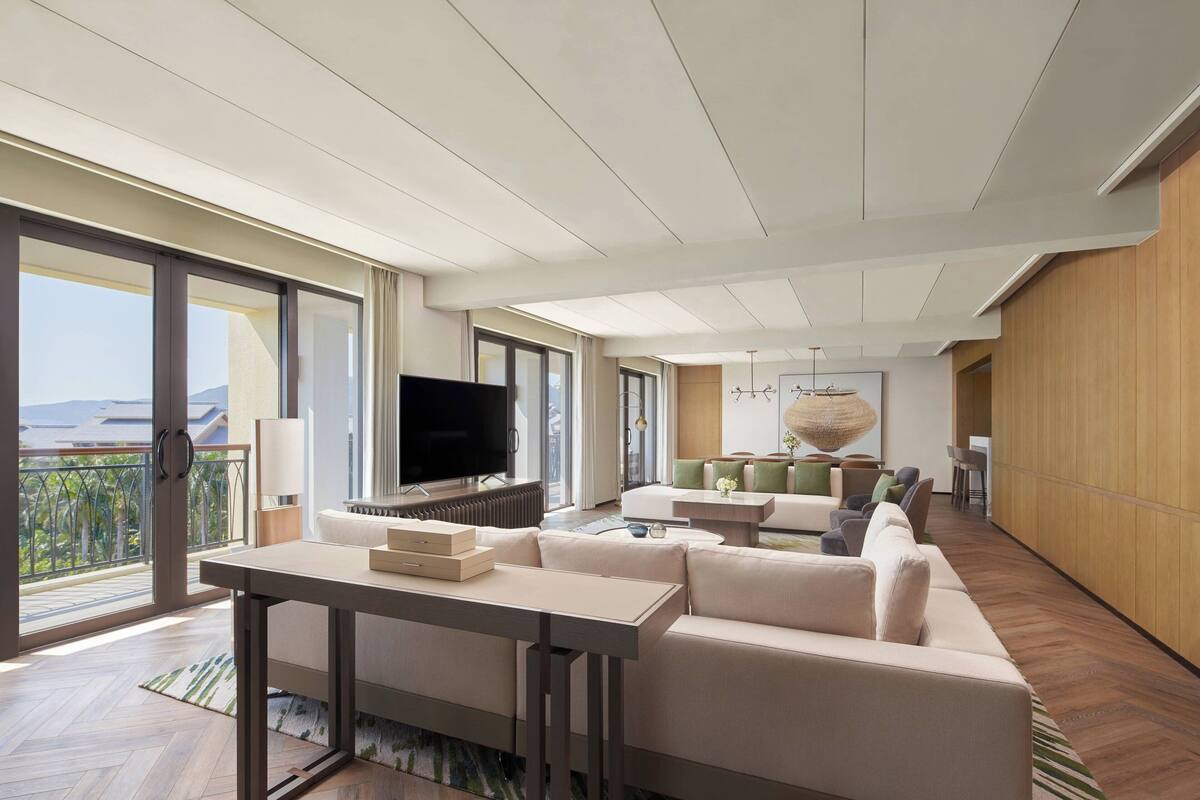 Un salon moderne avec un canapé, une table basse, un téléviseur et un balcon offrant une vue agréable.