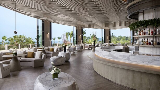 Een moderne lounge met een gebogen bar, comfortabele zithoek en grote ramen met uitzicht op zee.