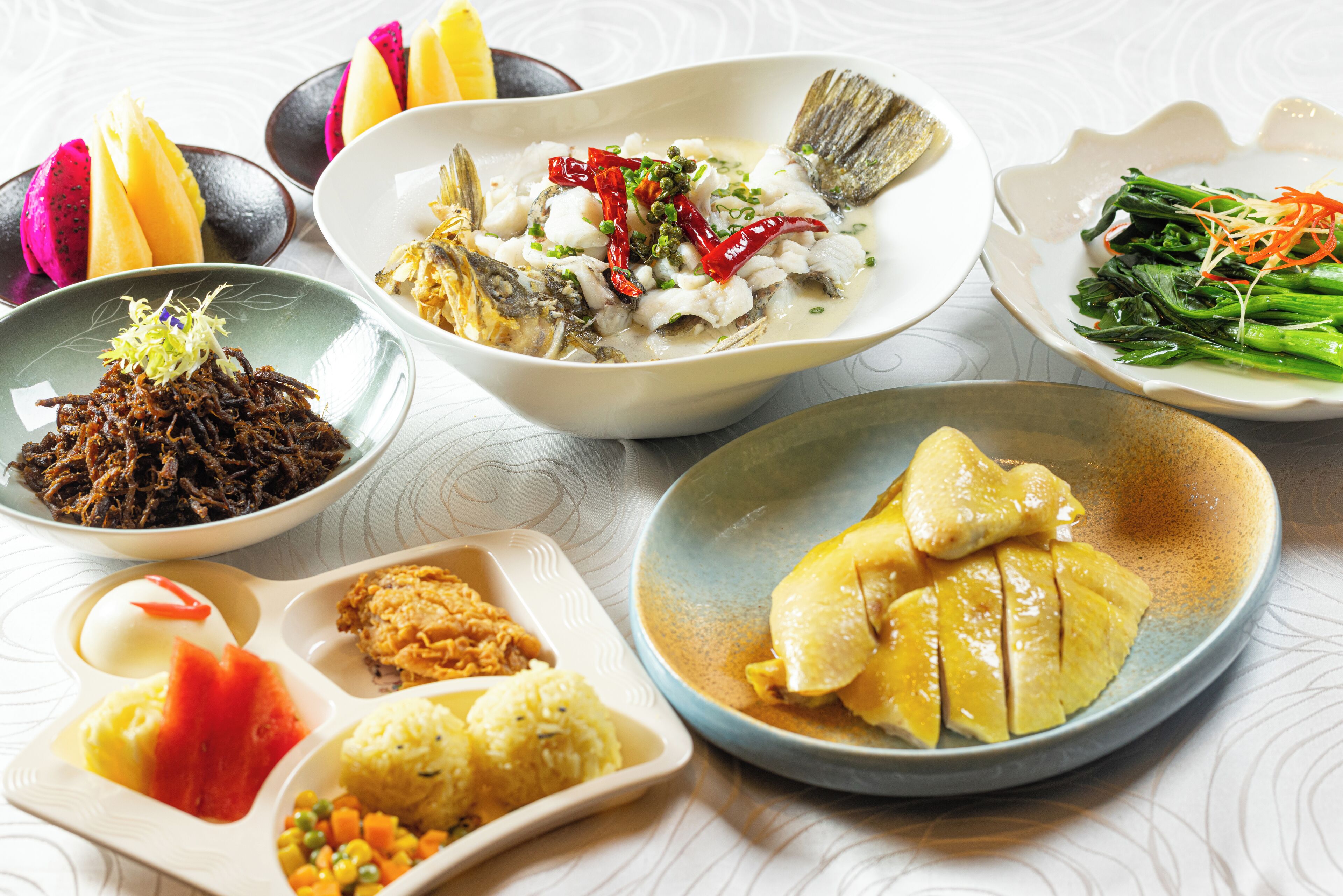 A variety of dishes including fish, vegetables, and rice, presented on multiple plates.