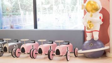 A row of vintage toy cars with numbers 1 to 3, a toy astronaut playing a saxophone, and a large blue ball with a music note.