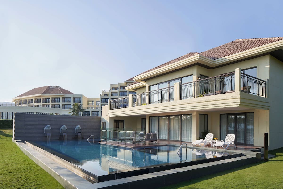 Une maison moderne à deux étages dotée d’une piscine, d’un espace salon extérieur et d’un grand balcon.