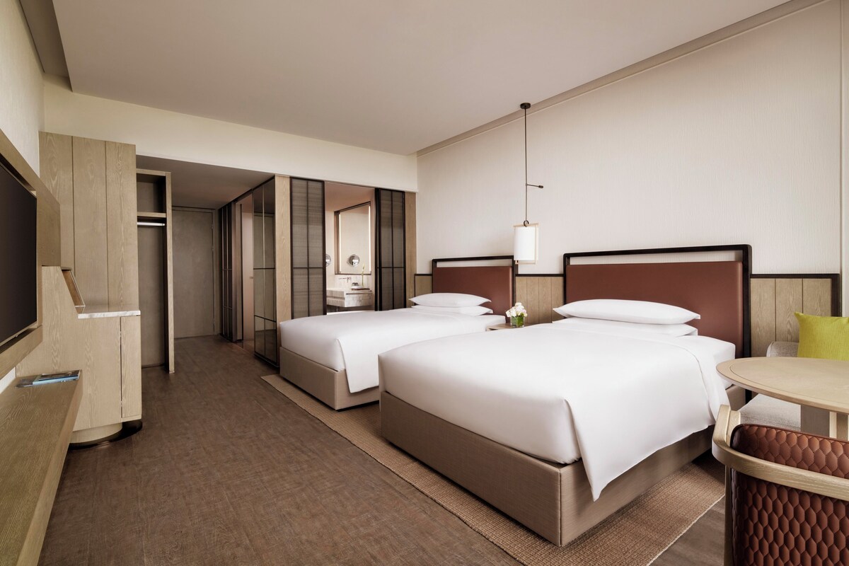 Een hotelkamer met twee bedden, een bureau en een spiegel.