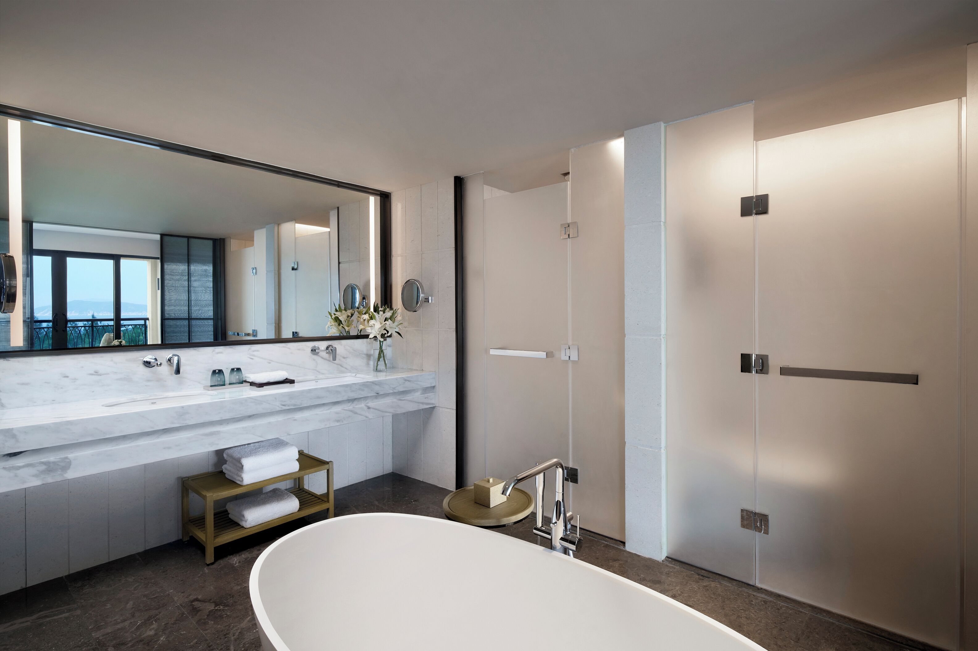 A modern bathroom with a large mirror, dual sinks, a bathtub, and a walk-in shower.