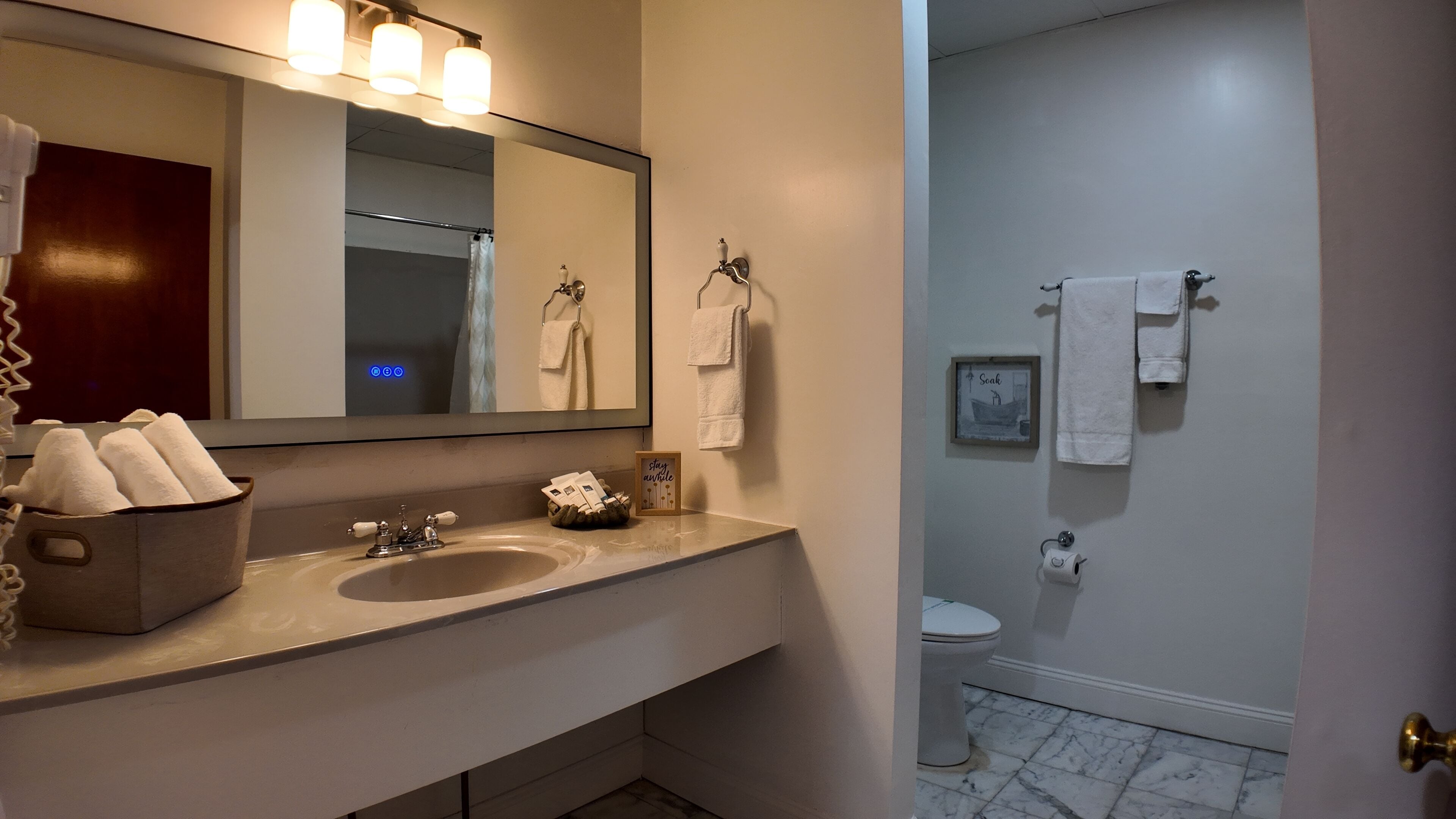 A bathroom with a sink, mirror, towel rack, and toilet.