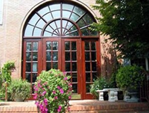 A brick building with a large arched window and a wooden door.