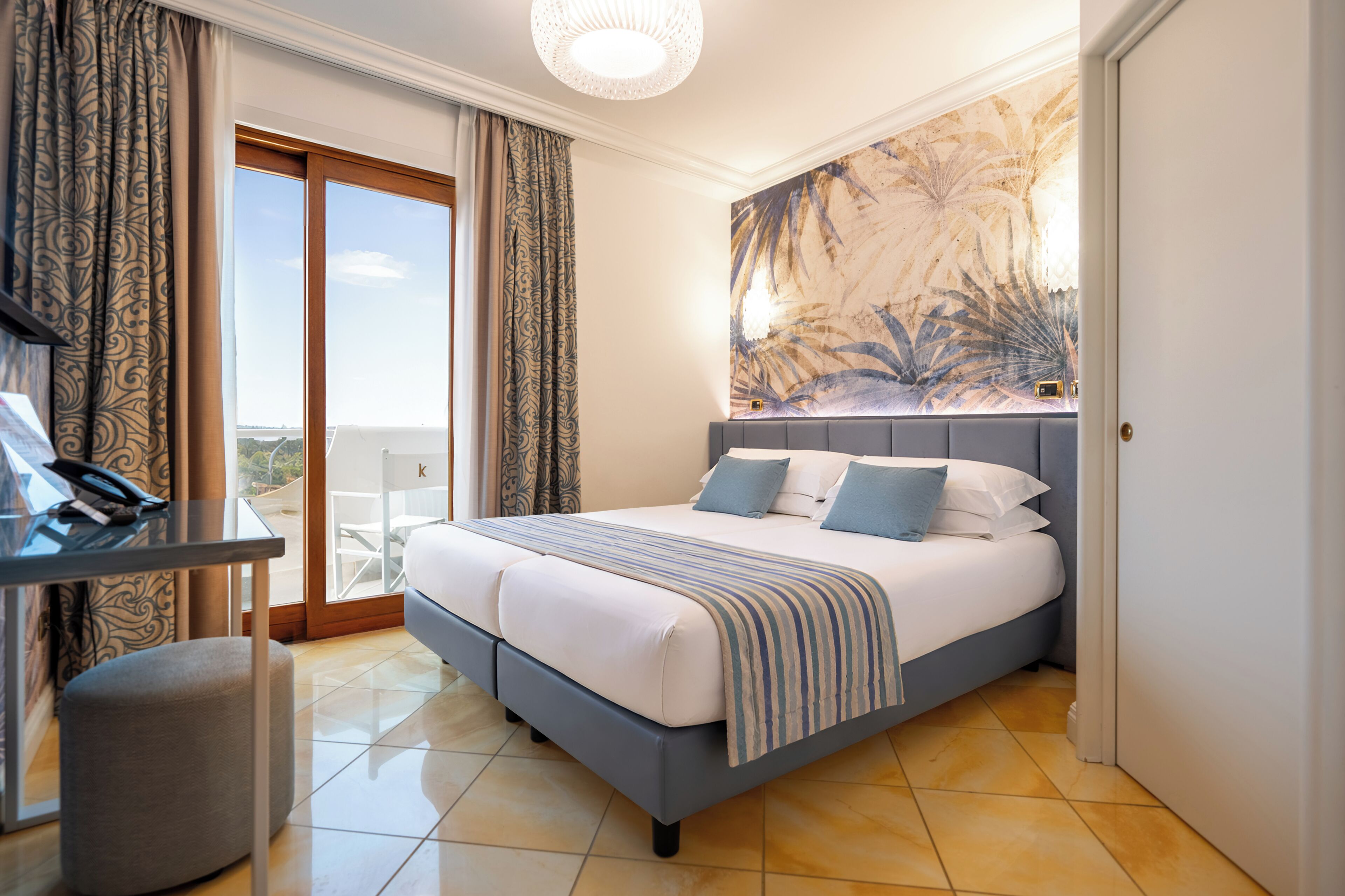Habitación de hotel con cama, escritorio y vistas al exterior.