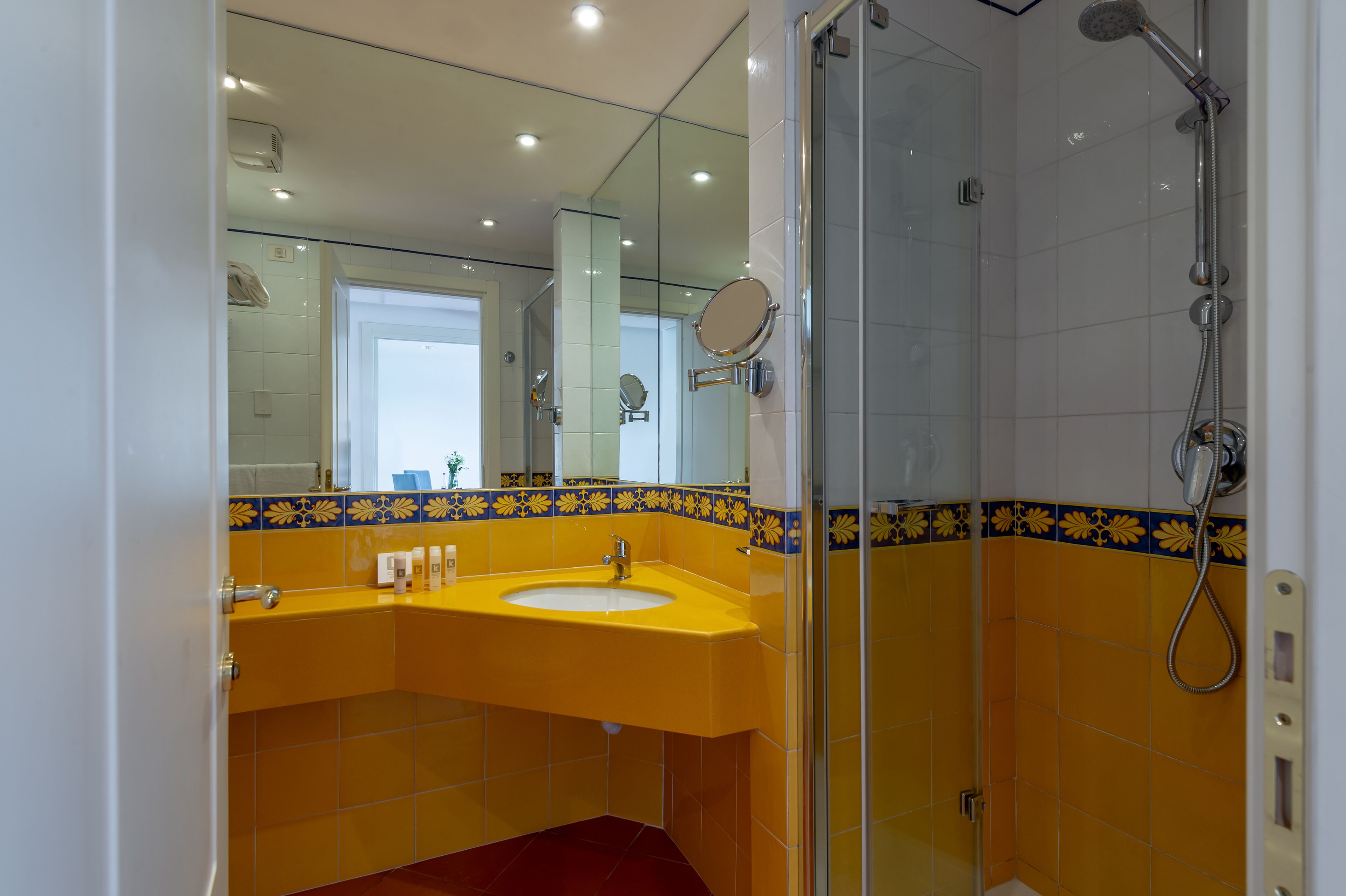 A bathroom with a yellow sink, a mirror, and a shower.