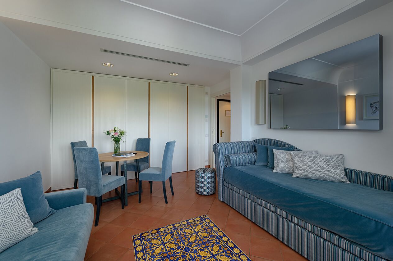Een moderne woonkamer met een bank, stoelen, een klein tafeltje en een kamerkleed met een patroon.