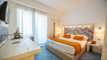 A hotel room with a bed, bedside table, and a desk with a chair.