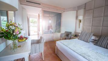 Una habitación de hotel con cama, mesita de noche, silla y ventana con cortinas.