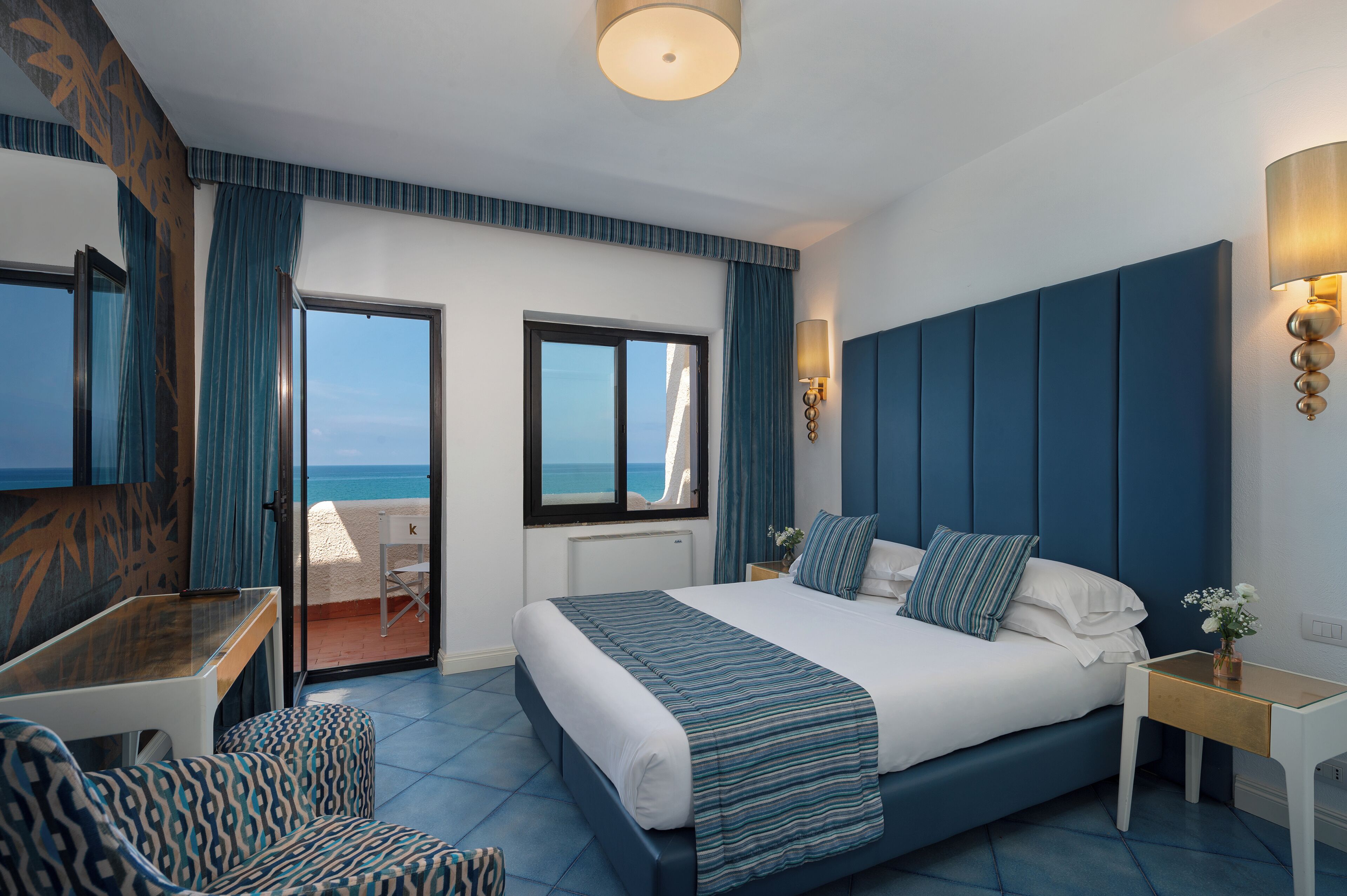 Ein modernes Hotelzimmer mit einem gro ßen Bett, einem Schreibtisch und Meerblick.