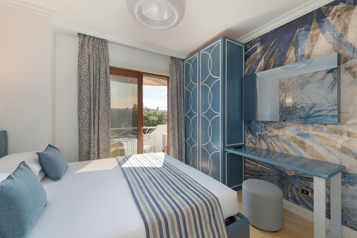 A hotel room with a bed, a desk, and a view of the outdoors.