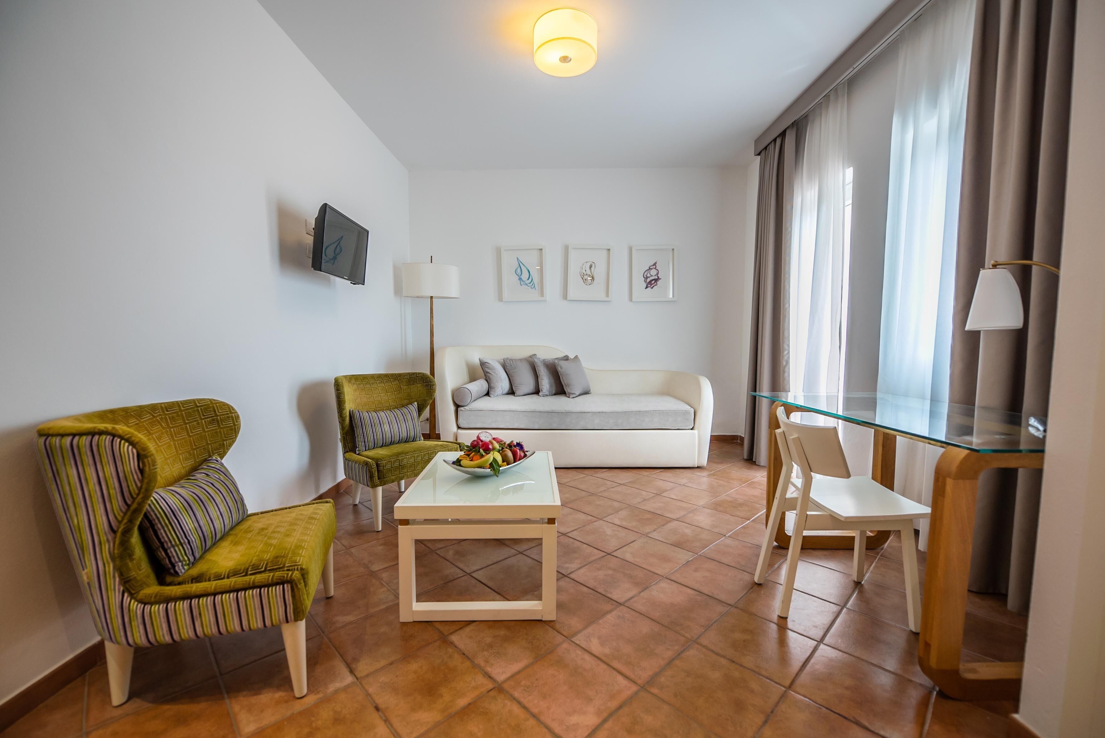 Una sala de estar moderna con un sofá, dos sillones, una mesa de centro y una mesa de vidrio.