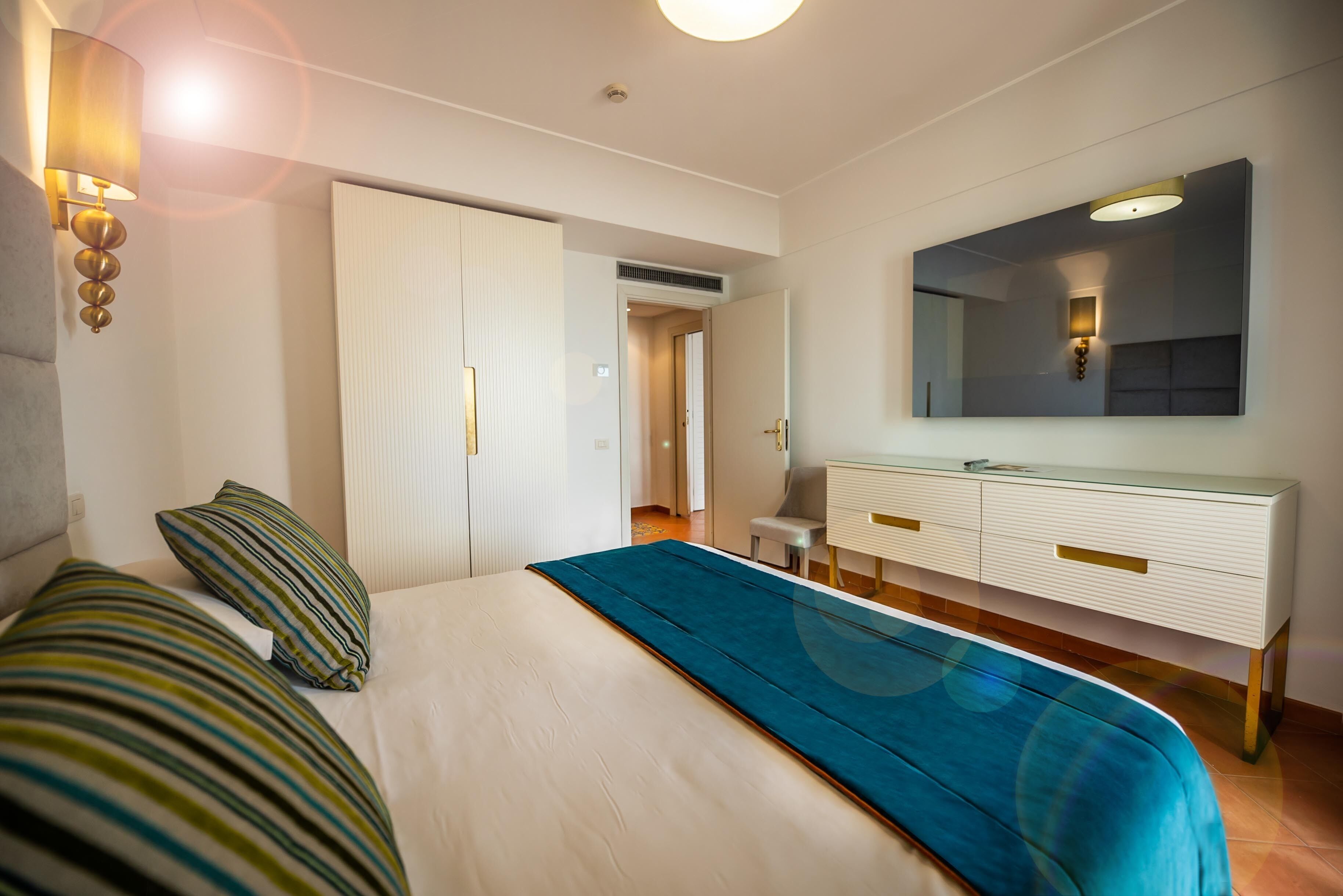 Una habitación de hotel con una cama, un tocador, un espejo y una puerta.