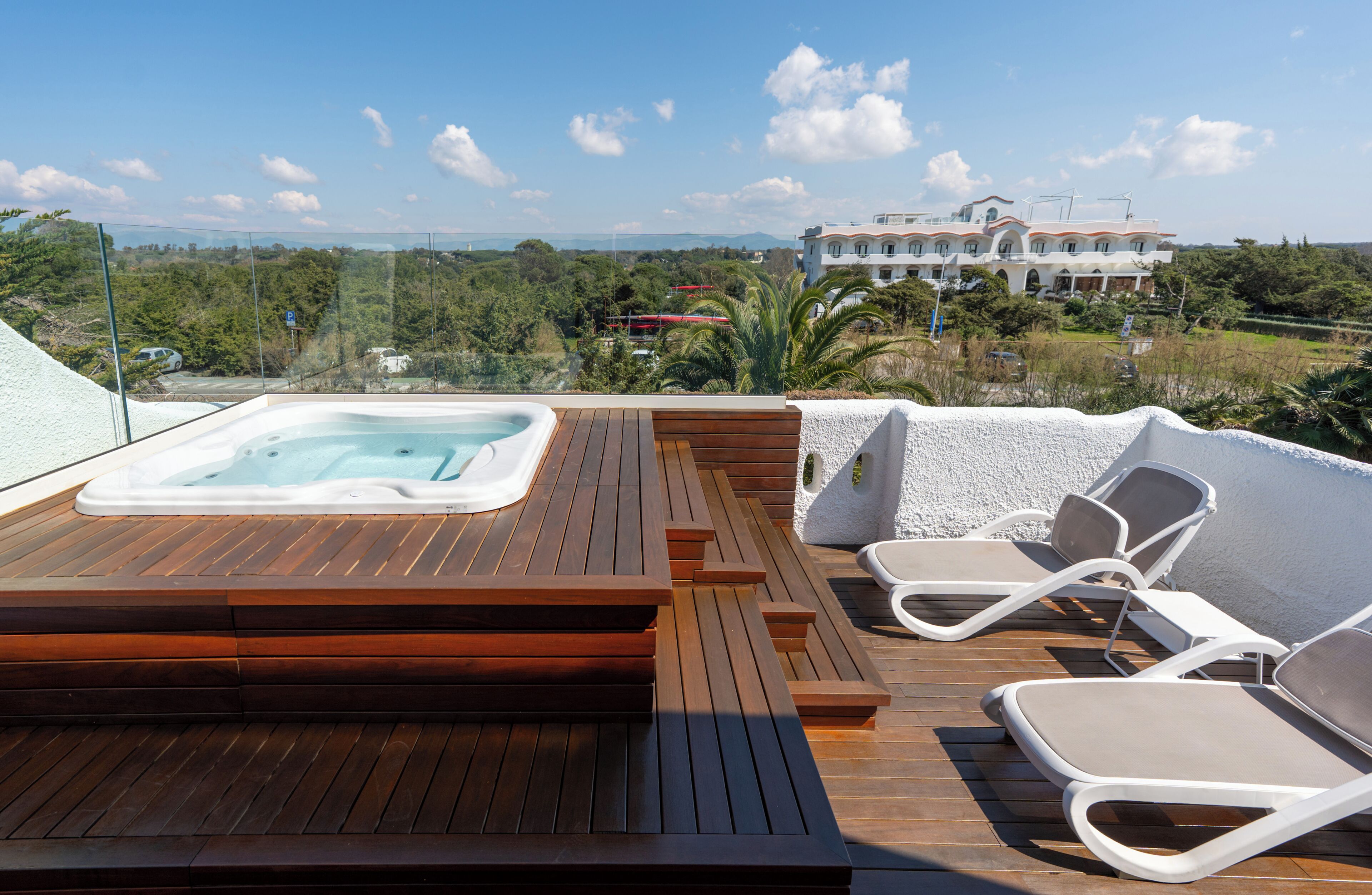 A rooftop terrace with a hot tub, wooden deck, and lounge chairs.