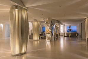 Un hall d’hôtel spacieux et moderne, doté de colonnes élégantes en métal et d’un design minimaliste.