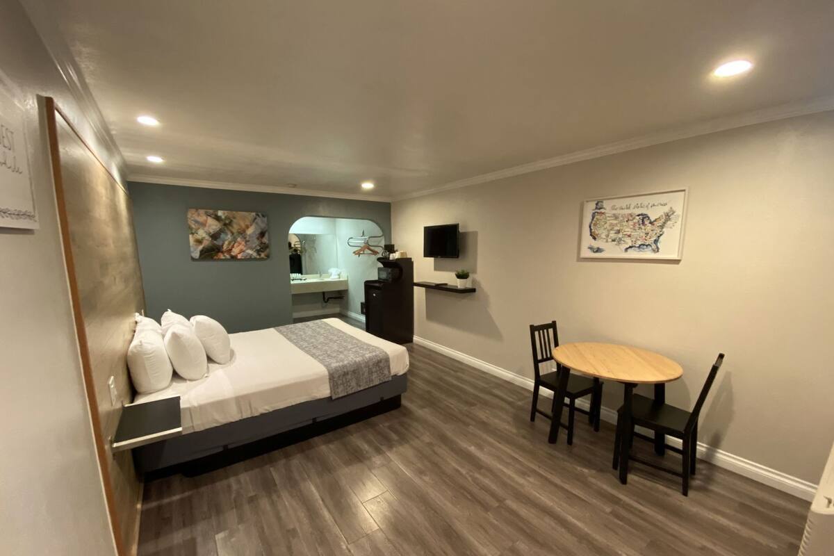 Un dormitorio con cama, escritorio, silla, televisión y un mapa en la pared.