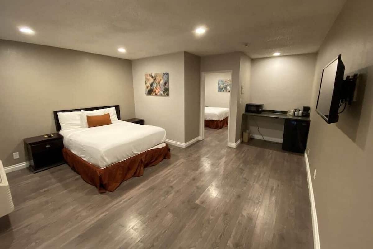 Un dormitorio con cama, escritorio, silla y televisor.