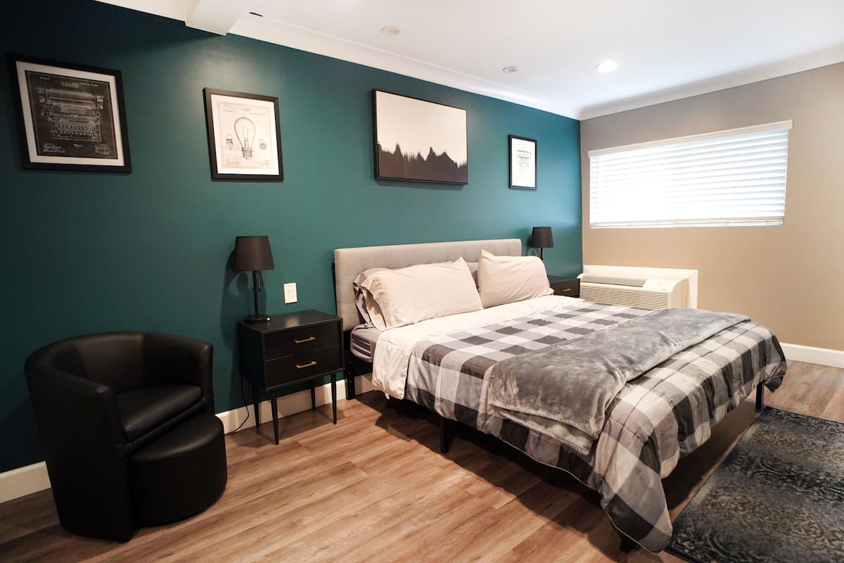 A bedroom with a bed, a chair, a nightstand, and a dresser.