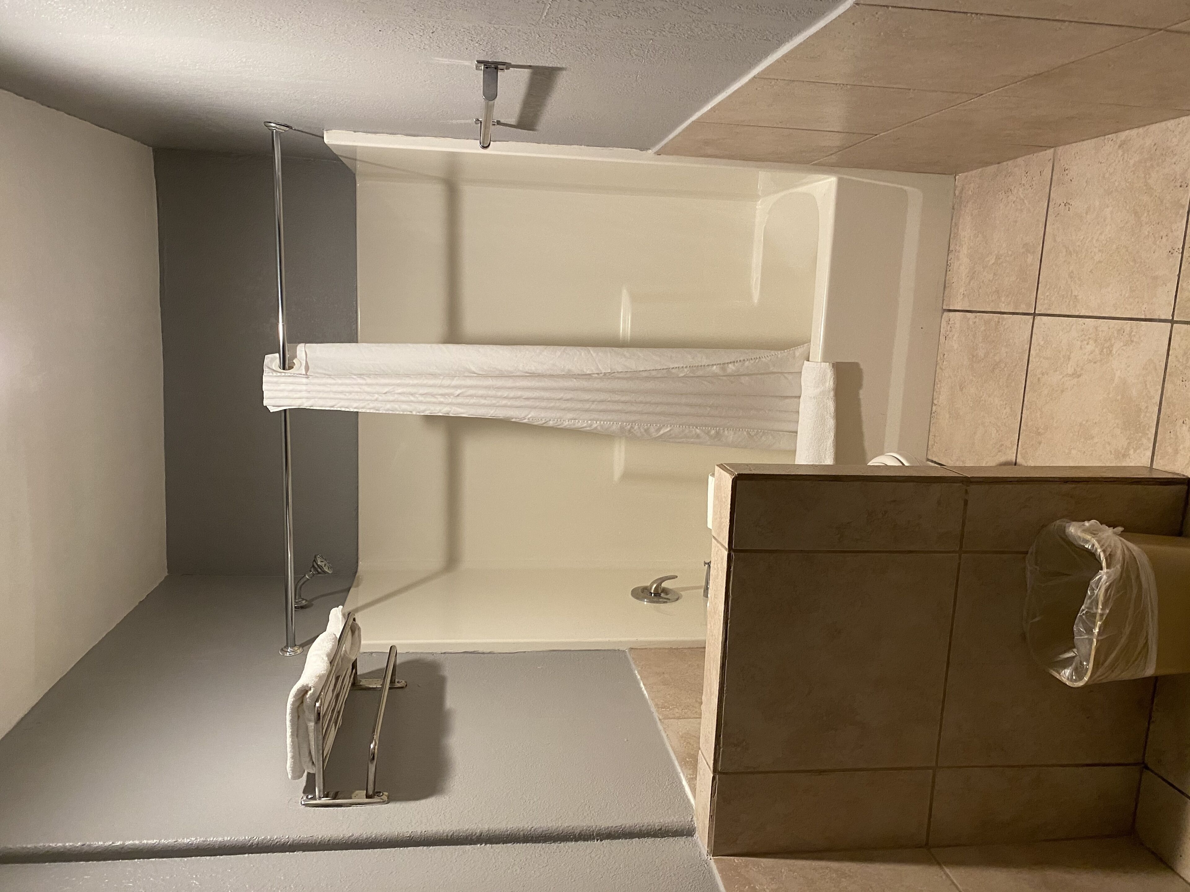 A bathroom with a shower, a towel rack, and a toilet.