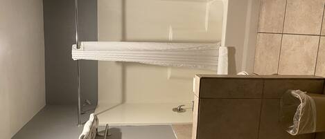 A bathroom with a shower, a towel rack, and a toilet.