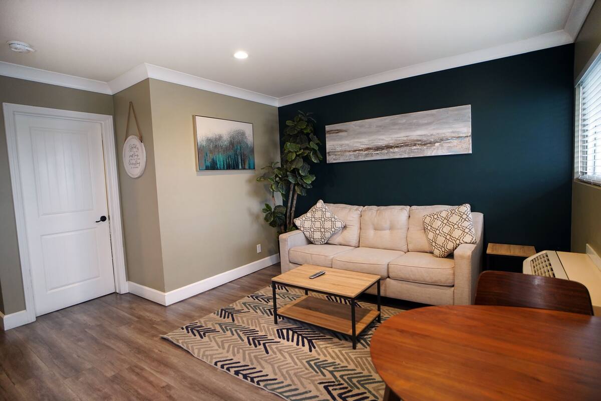 A living room with a beige sofa, a wooden coffee table, and a patterned rug.