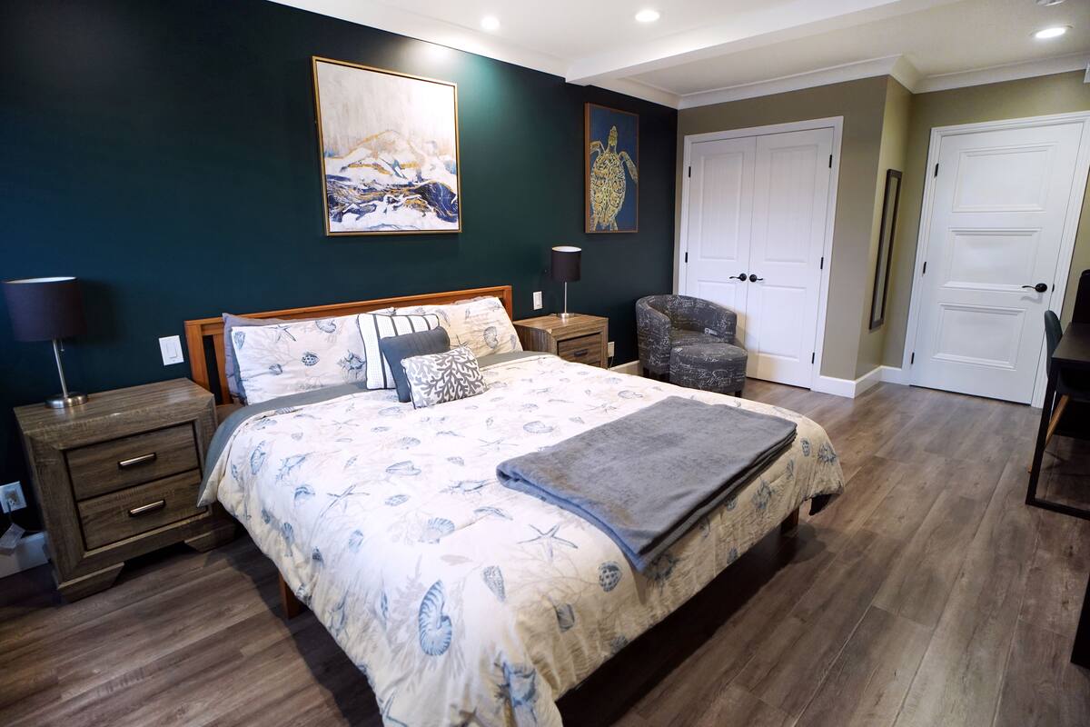 A bedroom with a large bed, two bedside tables, a chair, and two doors.
