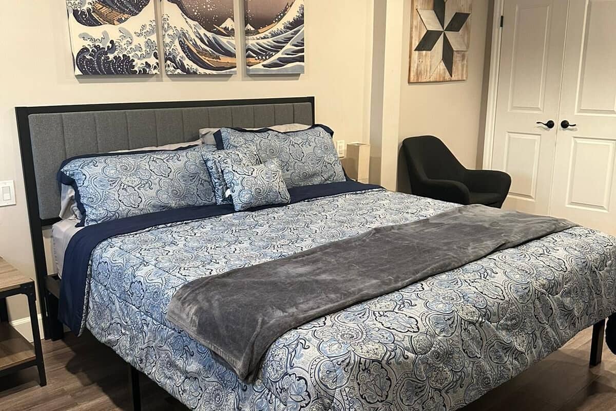 A bedroom with a bed, a chair, and artwork on the wall.