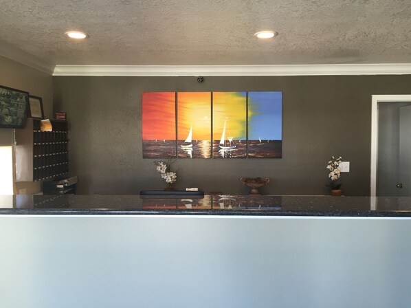 A reception area with a large painting of a sunset over the ocean, a reception desk, and a door to the right.