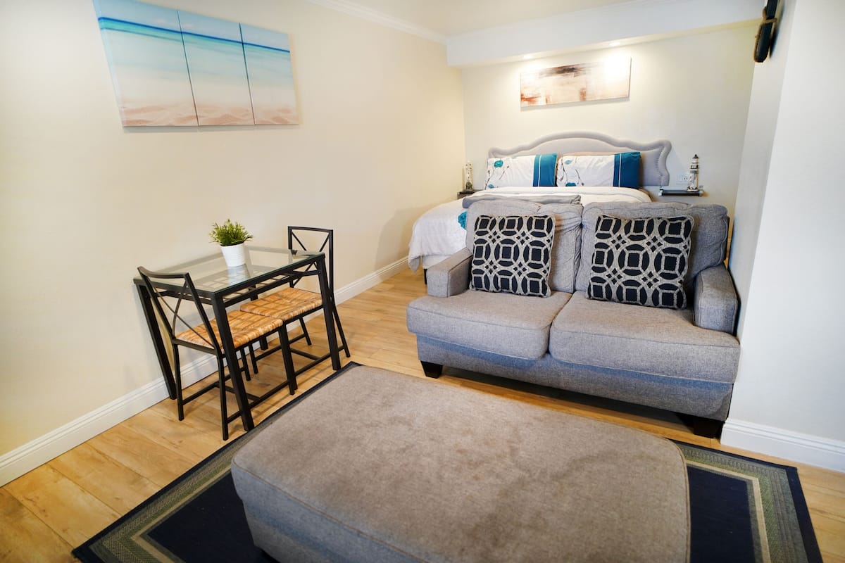 A compact living space with a sofa, ottoman, and a small table with chairs.