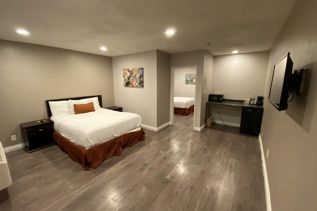 A bedroom with a large bed, a desk, and a television.