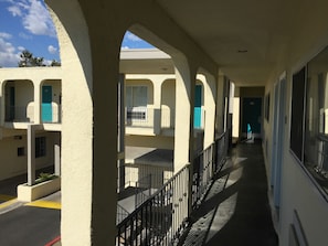 A corridor with balconies, a covered walkway, and a view of the street.
