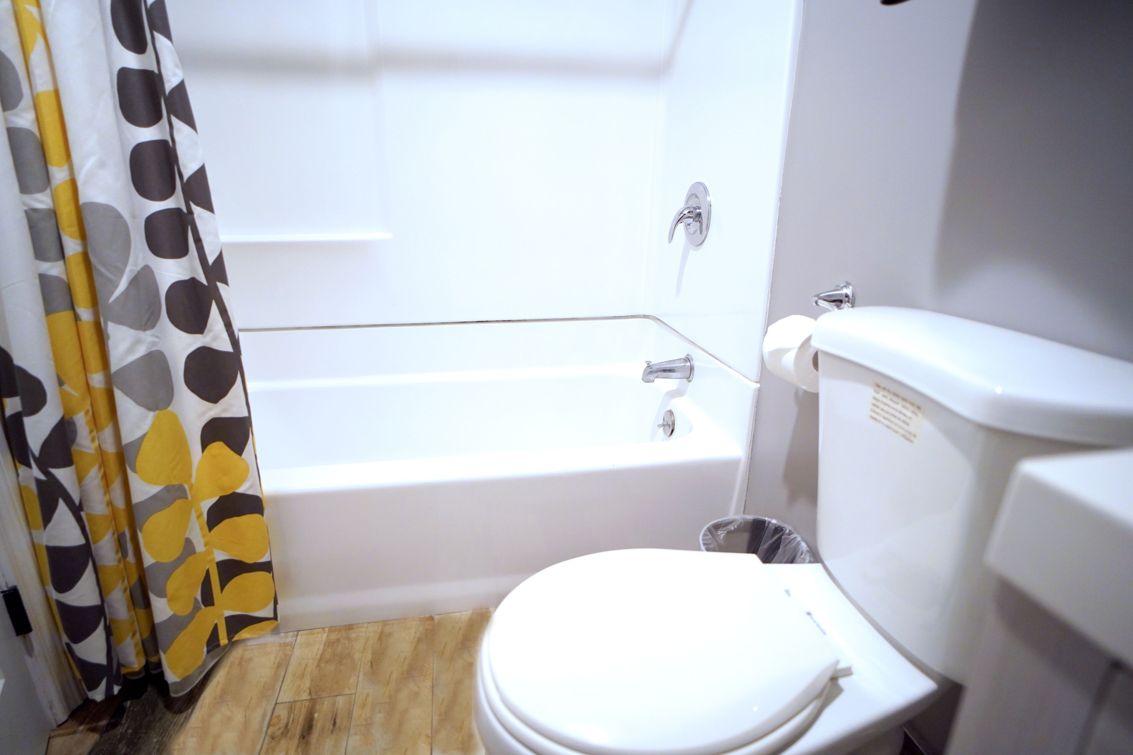 A bathroom with a white toilet, a bathtub, and a shower curtain with a geometric pattern.