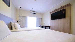 A hotel room with two beds, a desk, a TV, and an air conditioning unit. - Comfort Hotel Taguatinga (Taguatinga)