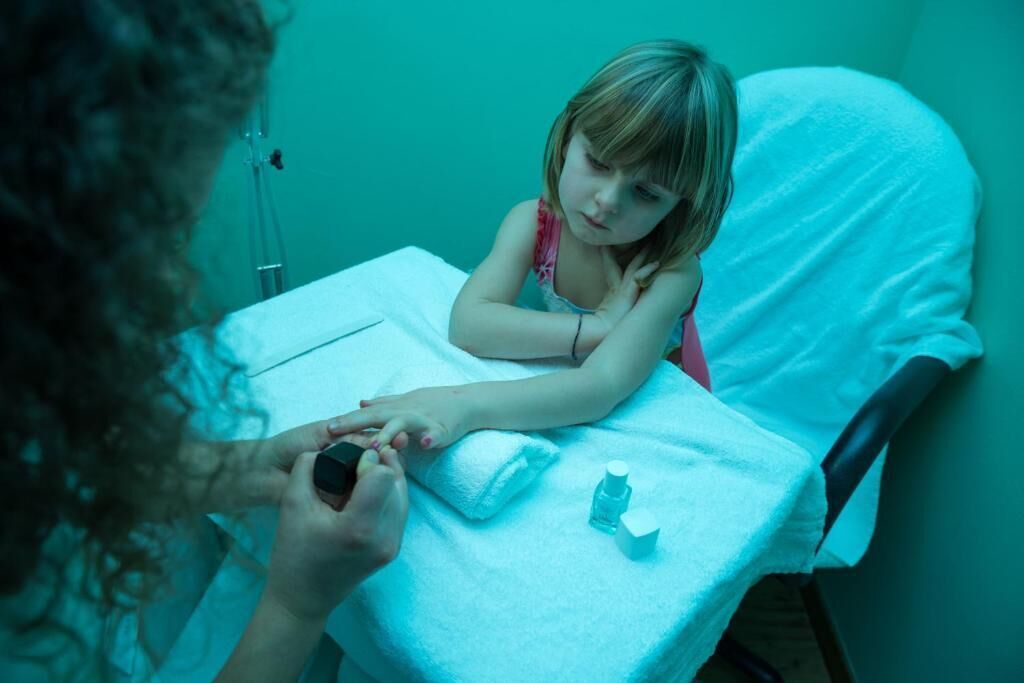 Un niño en una cama de hospital con un equipo médico conectado a su brazo, una almohada blanca y una botella sobre la cama.