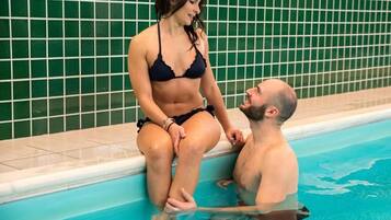 Ein Paar sitzt an einem Pool mit gefliesten Wänden.