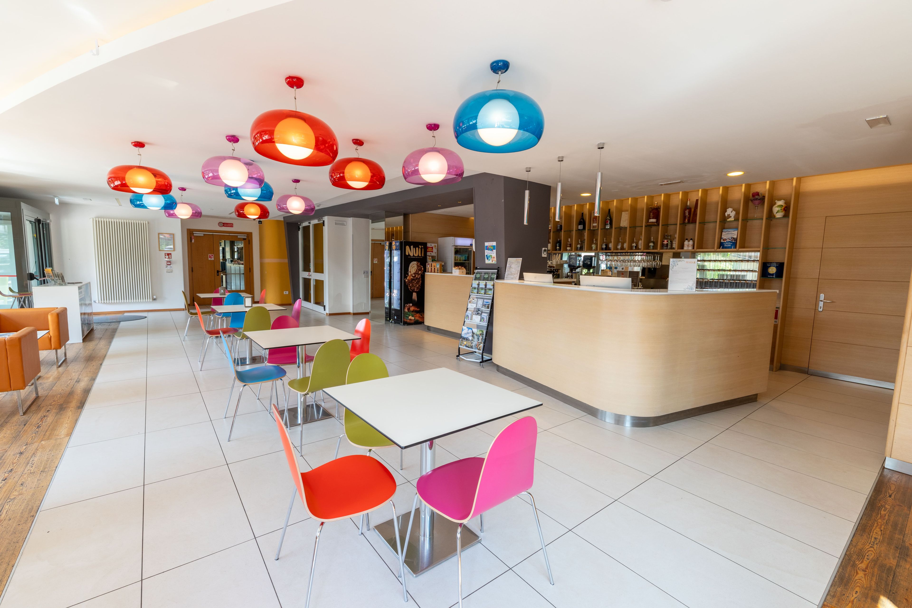 A modern interior with a reception desk, colorful chairs, and a variety of hanging pendant lights.