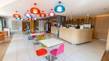 A modern interior with a reception desk, colorful chairs, and a variety of hanging pendant lights.