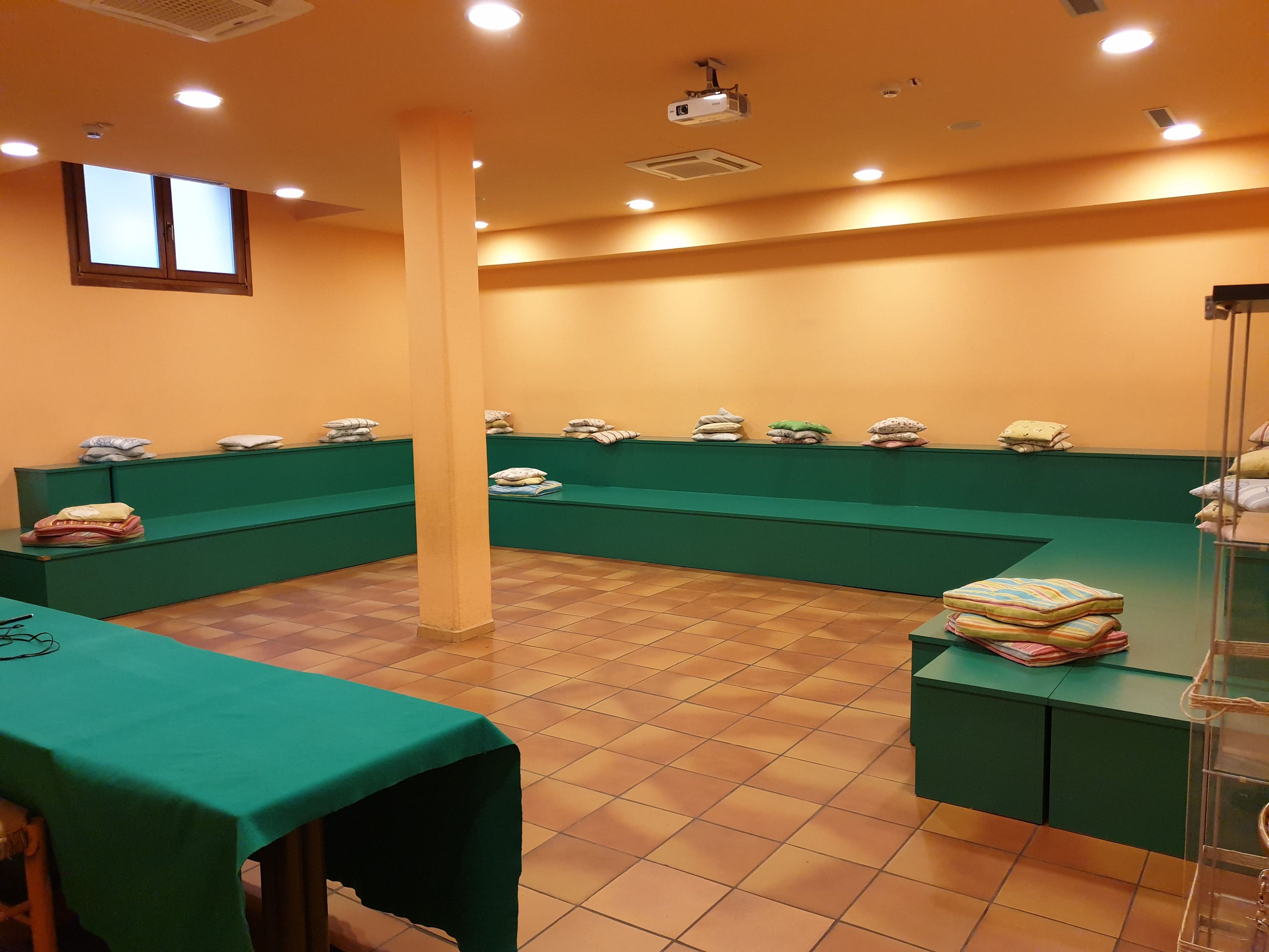 A room with green seating, a projector, and a window.