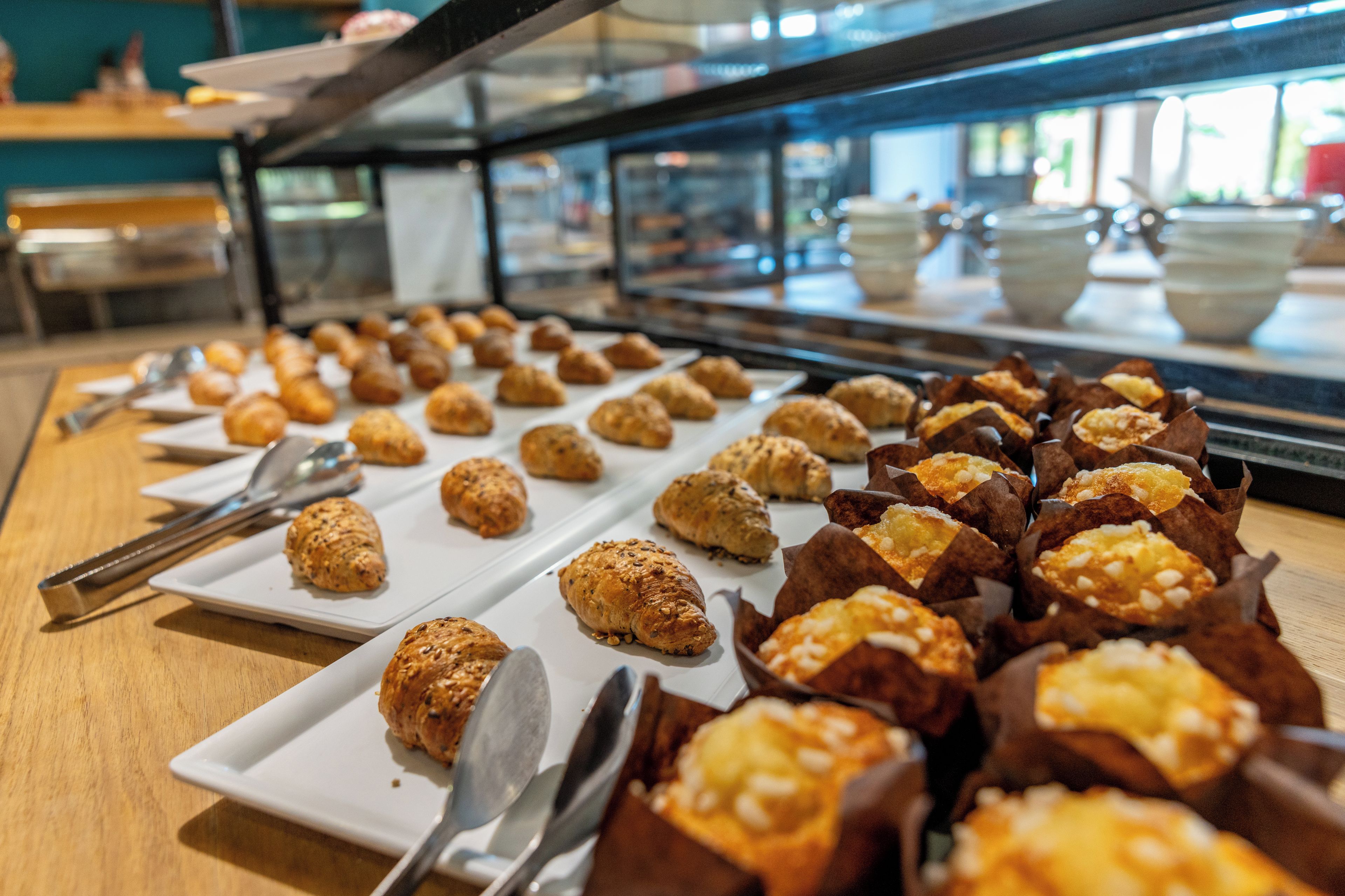 Un bufé con diversas pastelerías y productos de panadería exhibidos en platos y recipientes de papel.