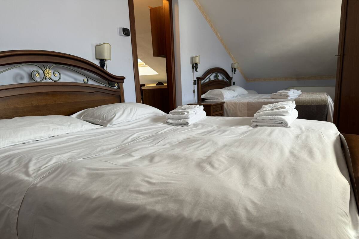 Habitación de hotel con dos camas, cada una con toallas impecablemente dobladas.