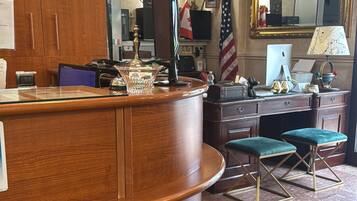 A reception area with a wooden desk, a flag, a computer, and a mirror.