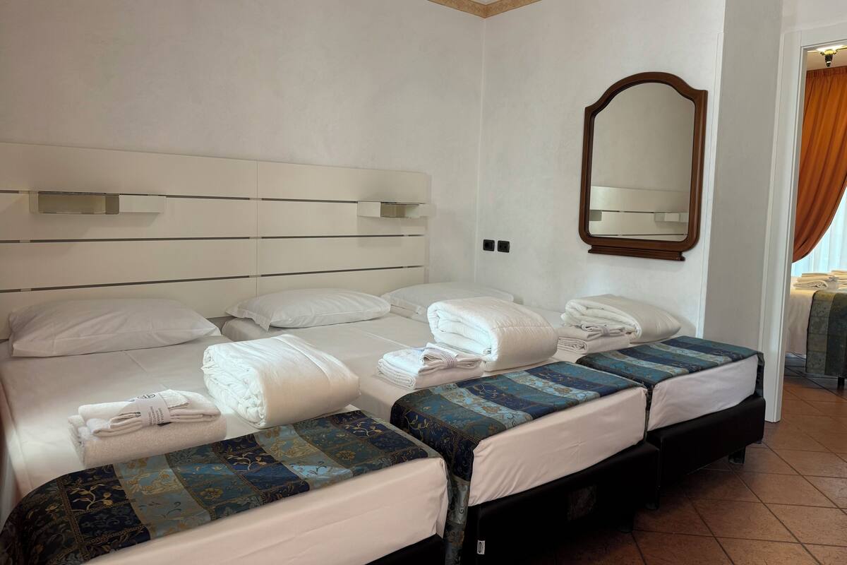 Ein Hotelzimmer mit zwei Betten, einem großen Spiegel und Blick nach draußen.
